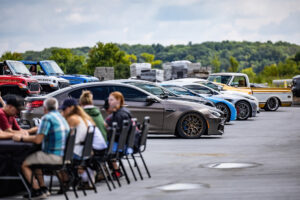 Owners and guests at a car show in the lot at The Hide Out Supermax Suites