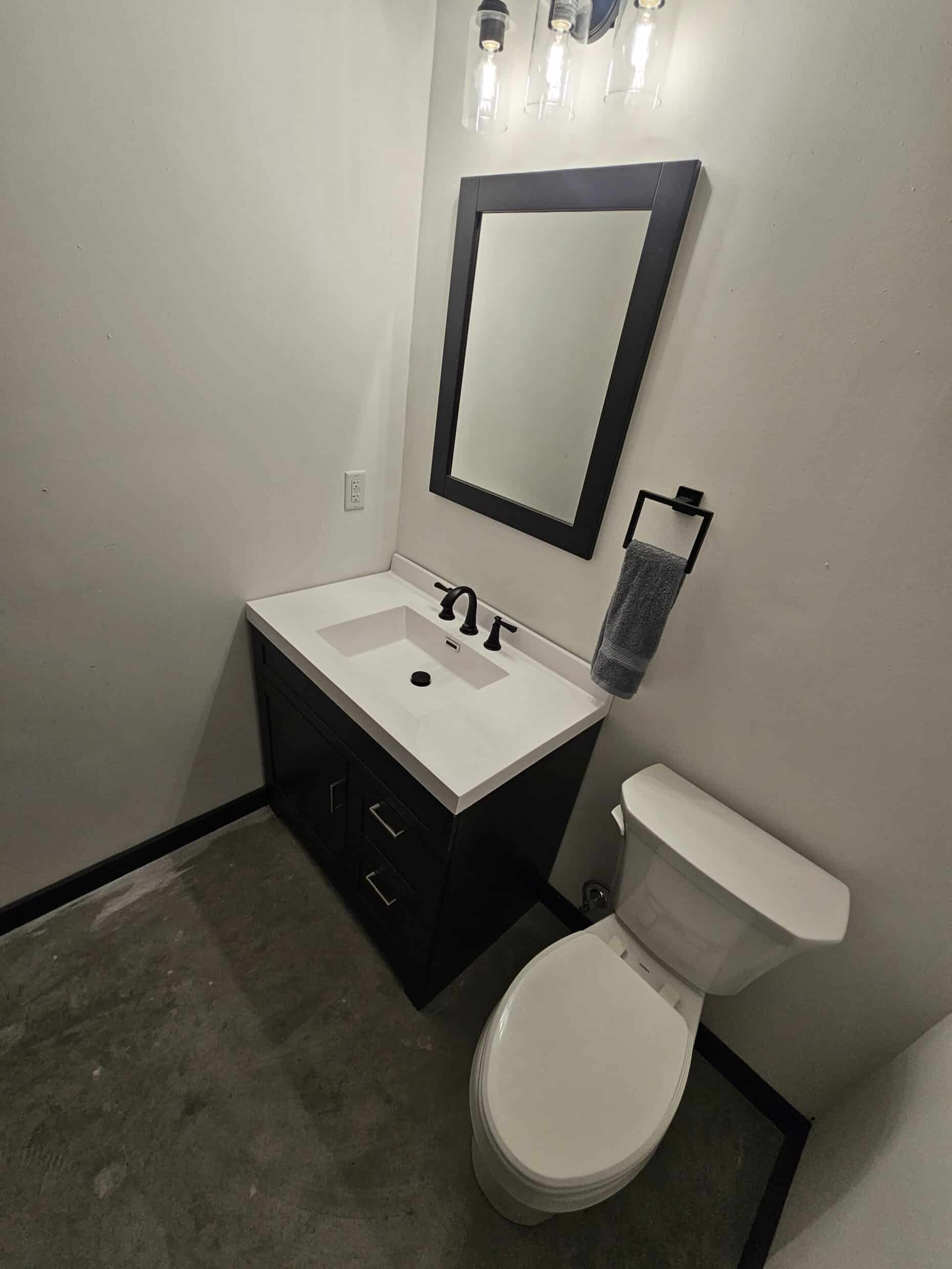 Finished bathroom in a Hide Out garage suite with vanity, sink, mirror and sconce