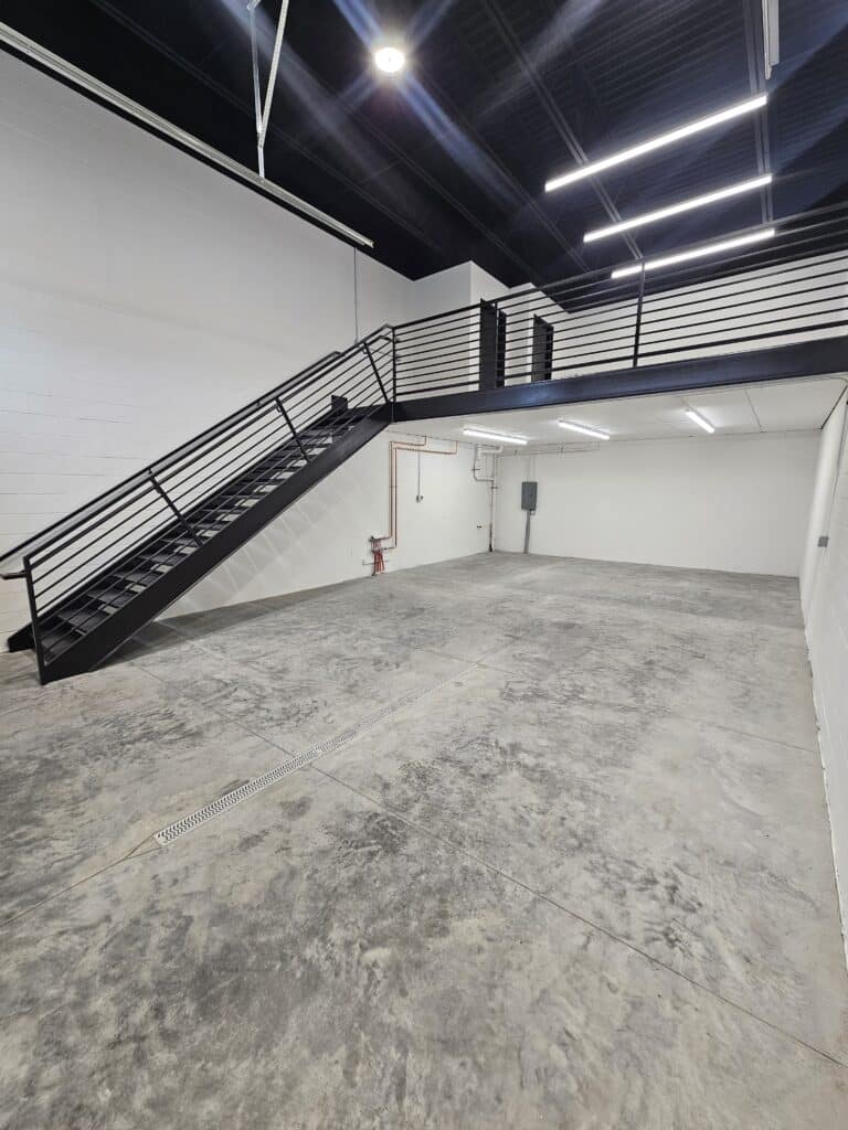 A Hide Out suite as delivered - painted block walls, sealed concrete floor and the steel stair up to the mezzanine