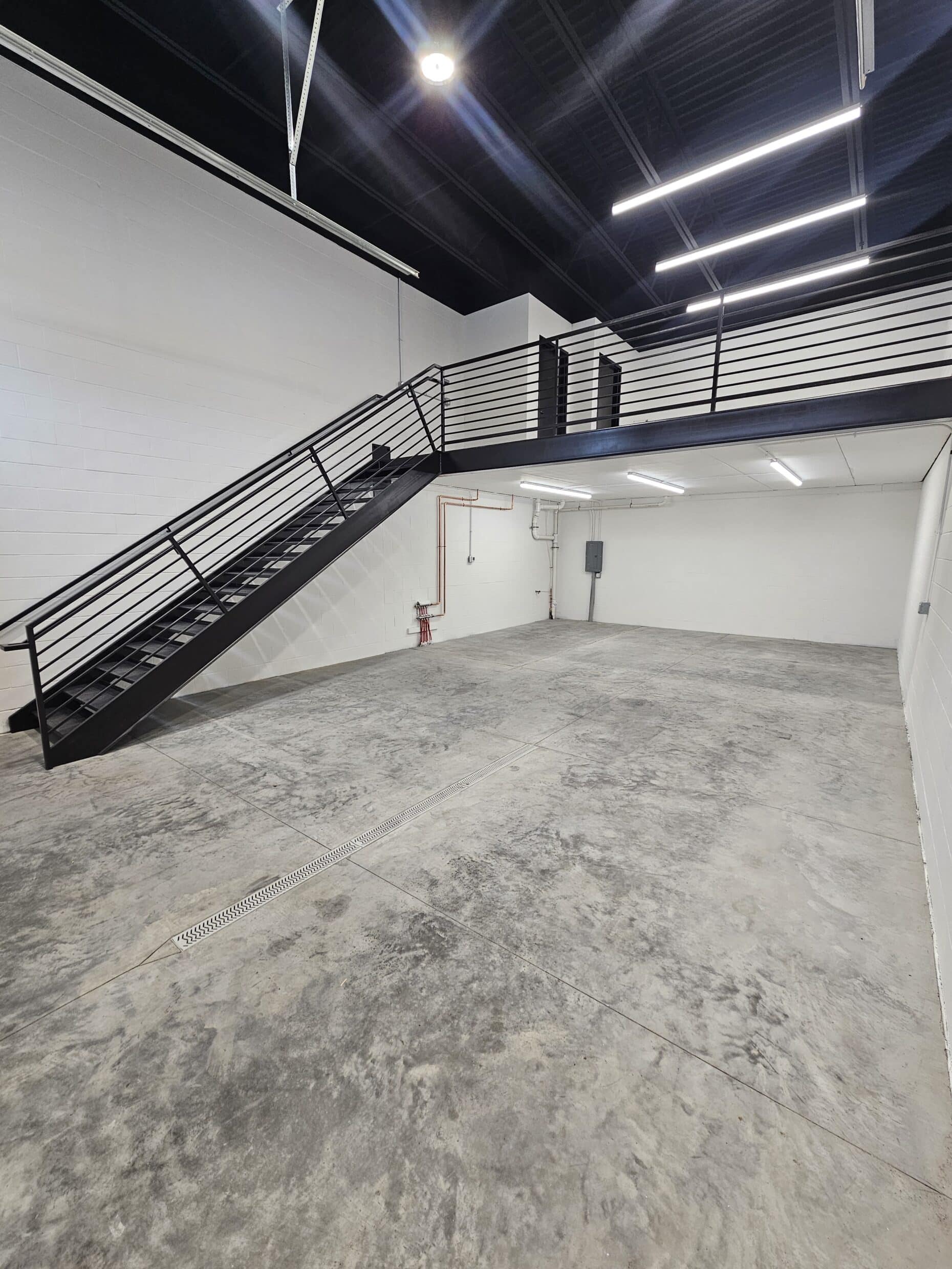 A Hide Out suite as delivered - painted block walls, sealed concrete floor and the steel stair up to the mezzanine