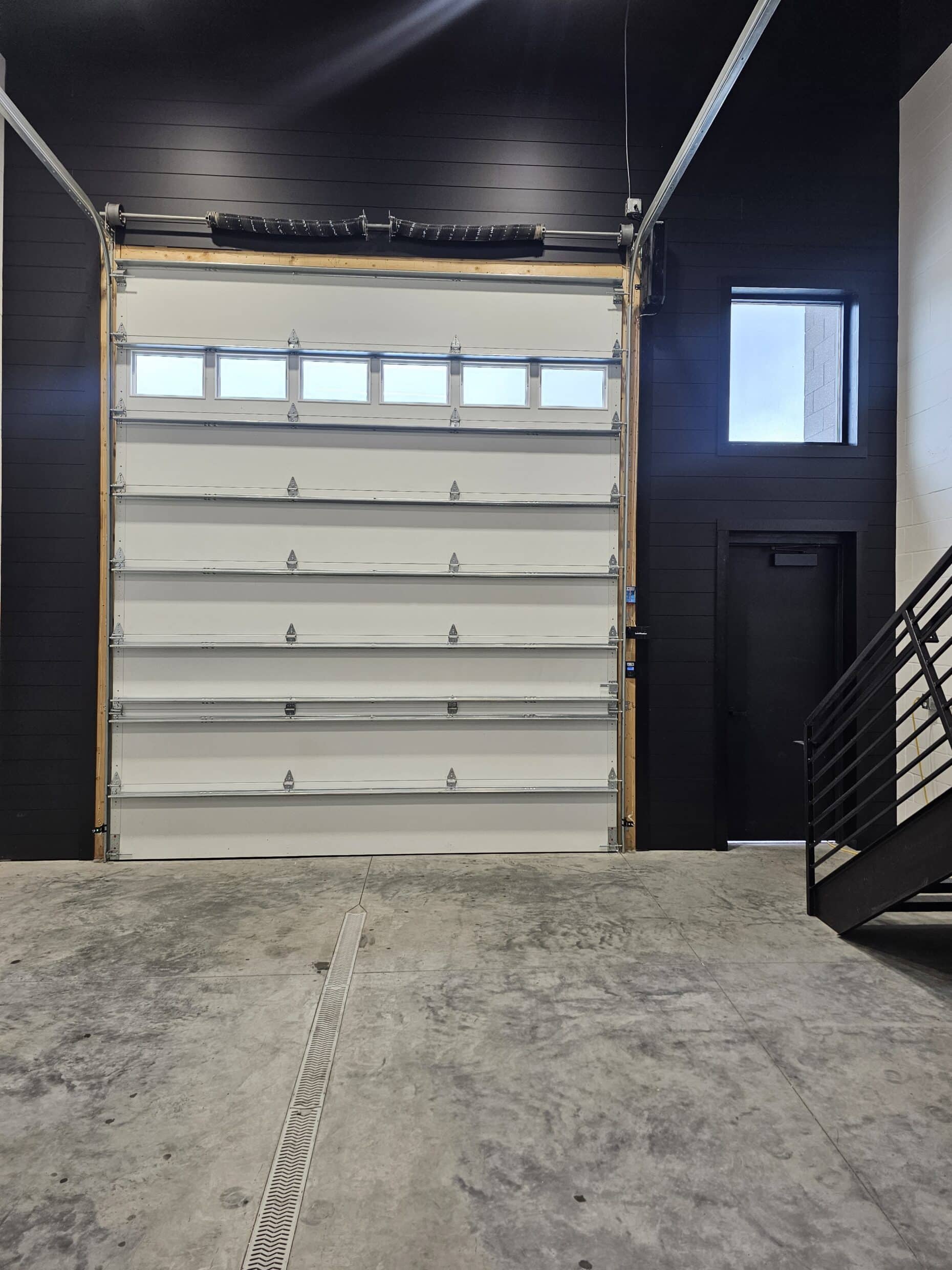 Insulated overhead door with window lites and the man door inside a Hide Out suite