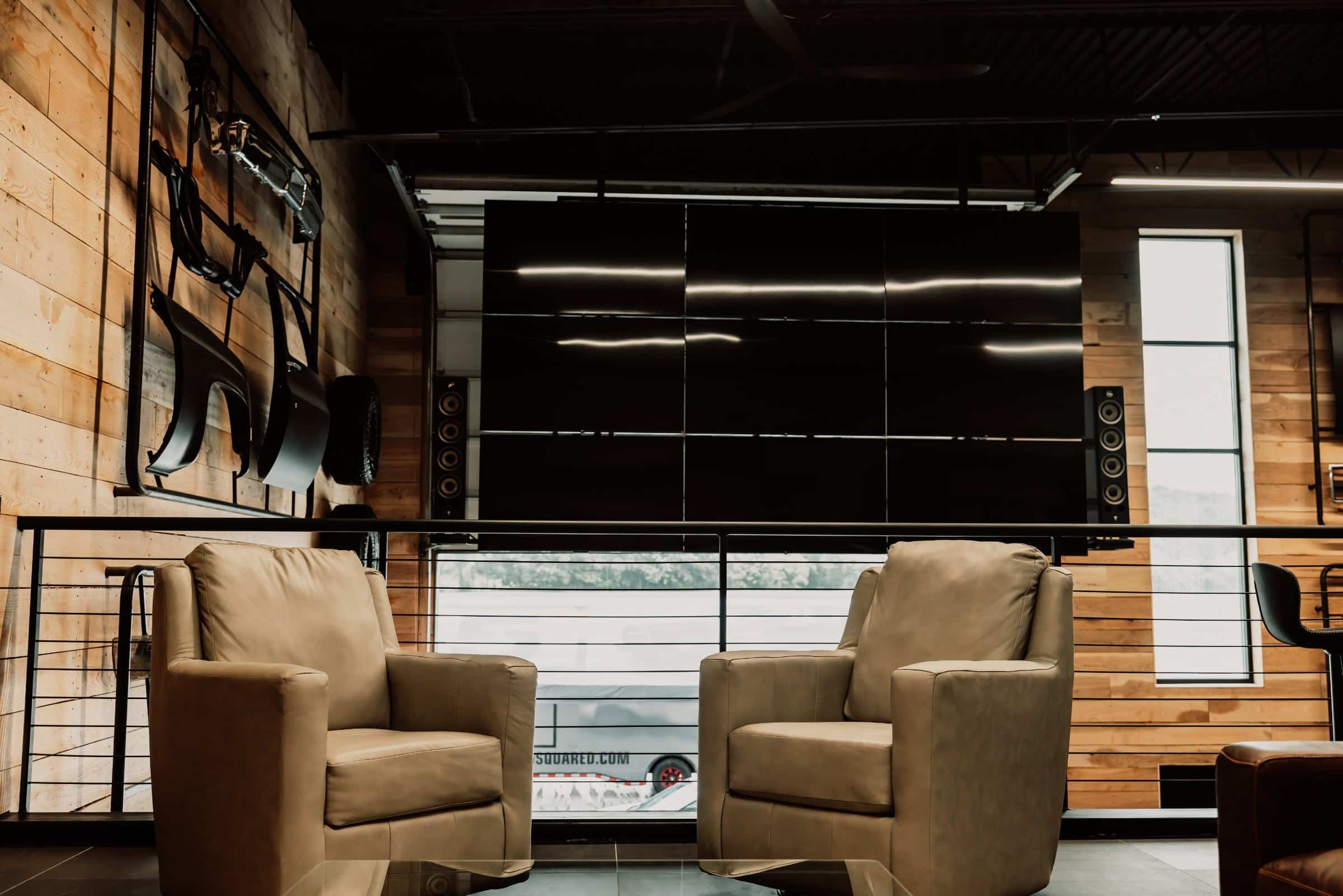 Finished garage condo lounge with a large screen wall and seating at The Hide Out